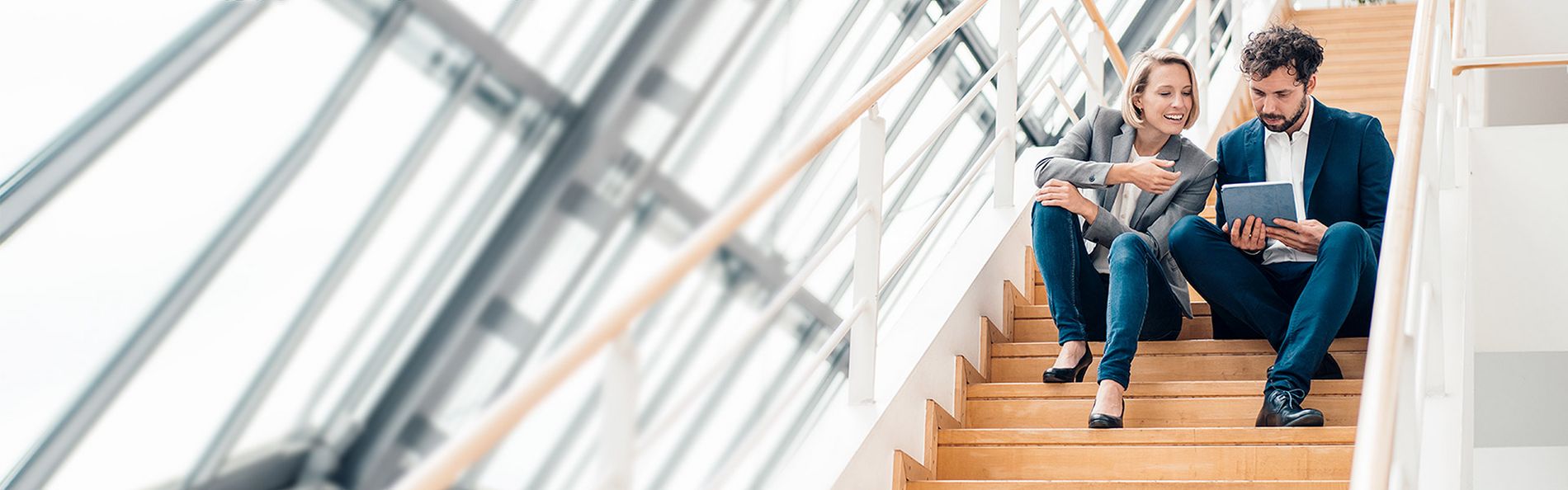 Zwei Personen sitzen mit einem Tablett auf einer Treppe