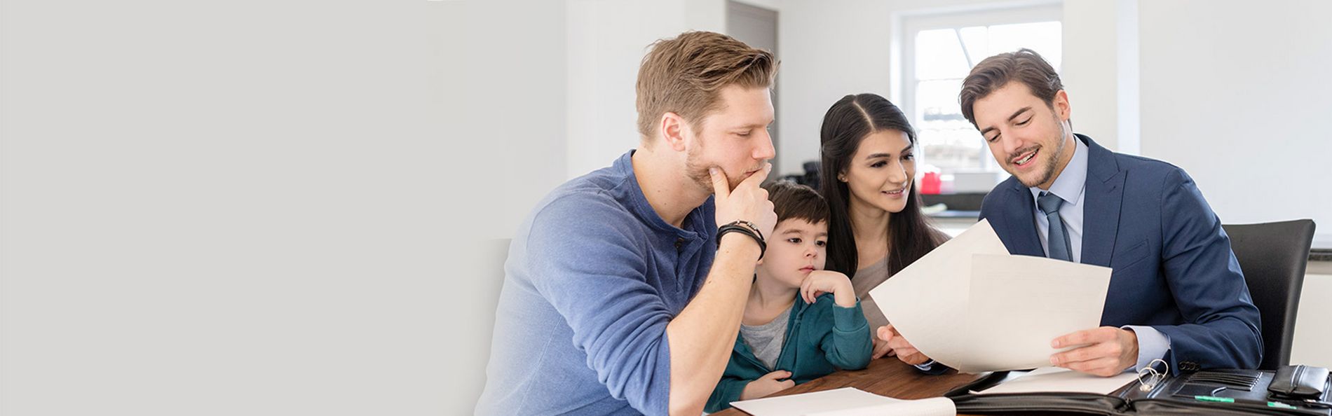 Vermittler sitzt mit Familie am Tisch und bespricht Unterlagen