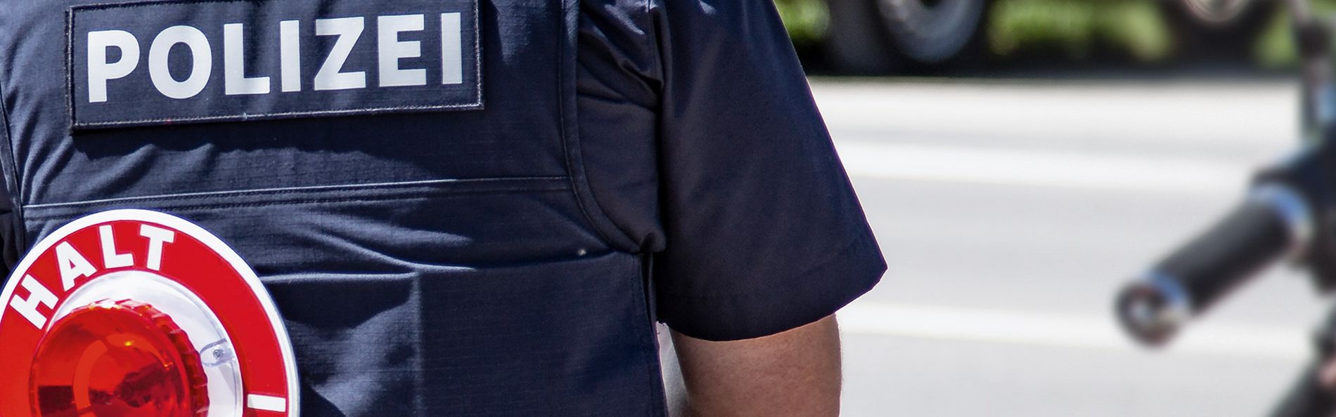 Berufsgruppe Polizei Polizist mit Schutzveste steht mit dem Rücken zur Kamera