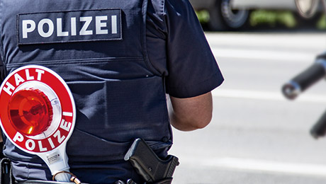 Polizist mit Schutzveste steht mit dem Rücken zur Kamera 