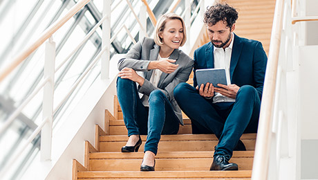 Zwei Personen sitzen mit einem Tablett auf einer Treppe