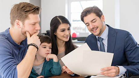 Vermittler sitzt mit Familie am Tisch und bespricht Unterlagen